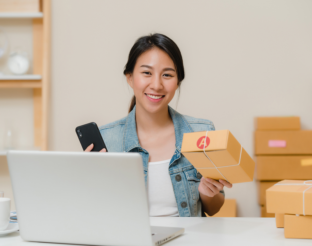 Smart Asian entrepreneur scanning QR code to check product stock at home